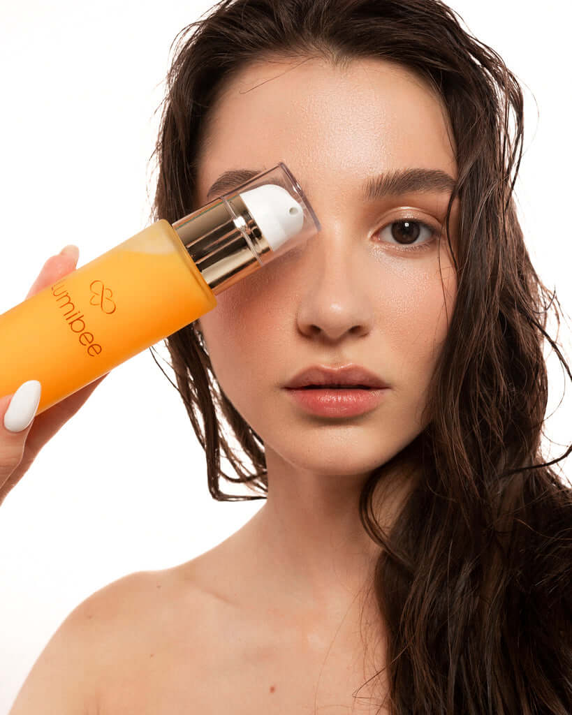 Close-up of a girl's face while holding a cleansing oil in front of her eye.